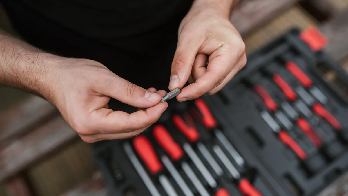 Hands handling a small screw over a tool case