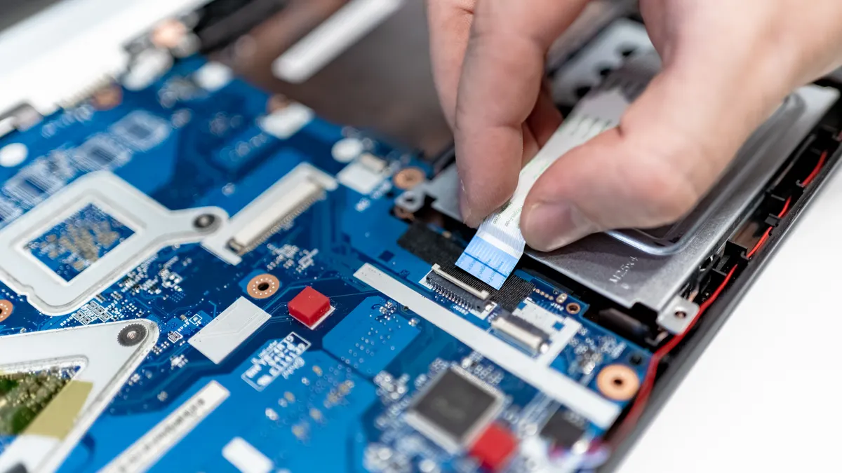 Laptop screwdriver sizes and bit types explained Close-up of screwdriver use on a laptop motherboard